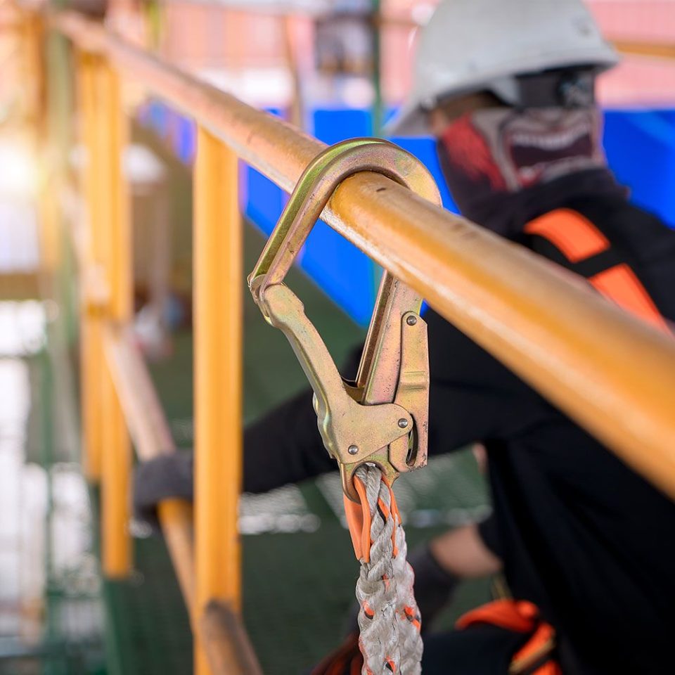 Close up of a rope safety harness with a man working in the background.